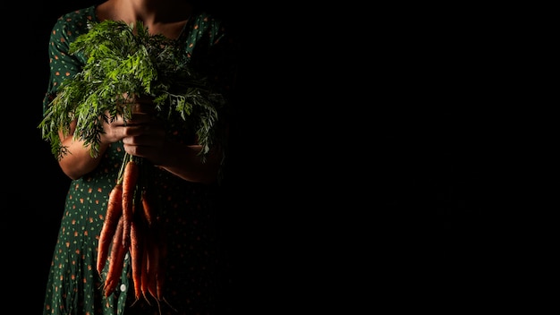 Photo gratuite vue de face femme tenant des carottes avec copie-espace