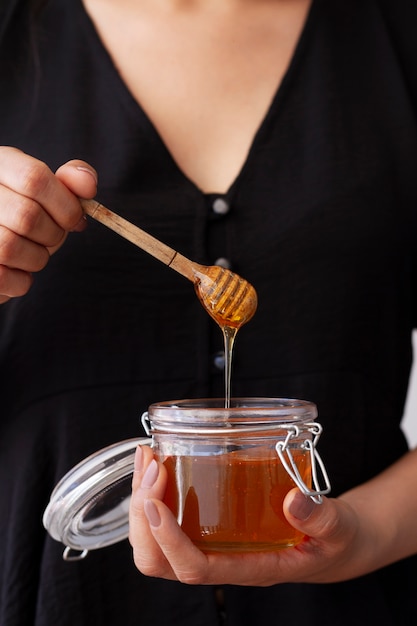 Photo gratuite vue de face d'une femme tenant un pot avec du miel et une louche de miel