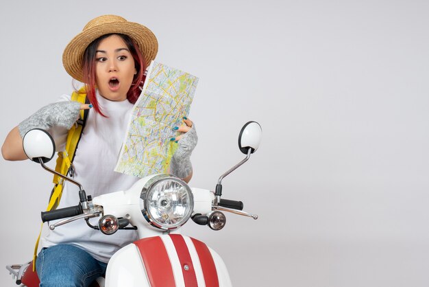 Vue de face femme touriste assise sur une moto avec mur blanc de carte