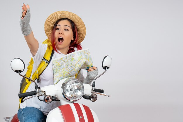 Vue de face femme touriste assise sur une moto avec mur blanc de carte