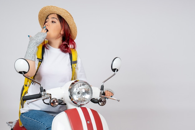 Photo gratuite vue de face femme touriste assise sur une moto sur un mur blanc