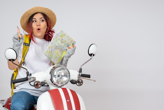 Vue de face femme touriste assise sur une moto tenant un mur blanc de carte