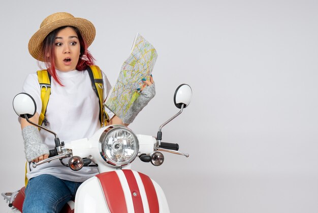 Vue de face femme touriste assise sur une moto tenant un mur blanc de carte