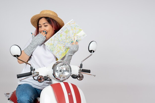 Vue de face femme touriste assise sur une moto tenant un mur blanc de carte