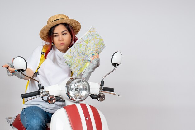 Vue de face femme touriste assise sur une moto tenant un mur blanc de carte
