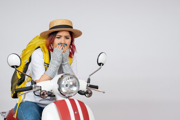 Vue de face femme touriste assise et posant sur une moto sur un mur blanc