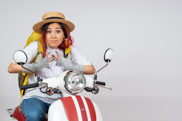 Vue de face femme touriste assise et posant sur une moto sur un mur blanc