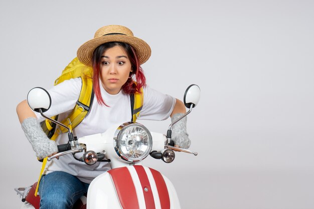 Vue de face femme touriste assise et posant sur une moto sur un mur blanc