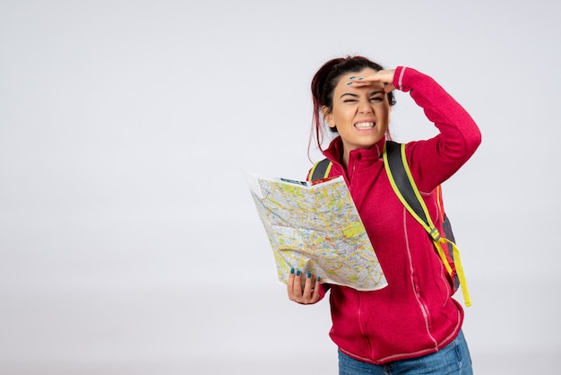 Vue de face femme touriste avec carte à la recherche de direction sur mur blanc