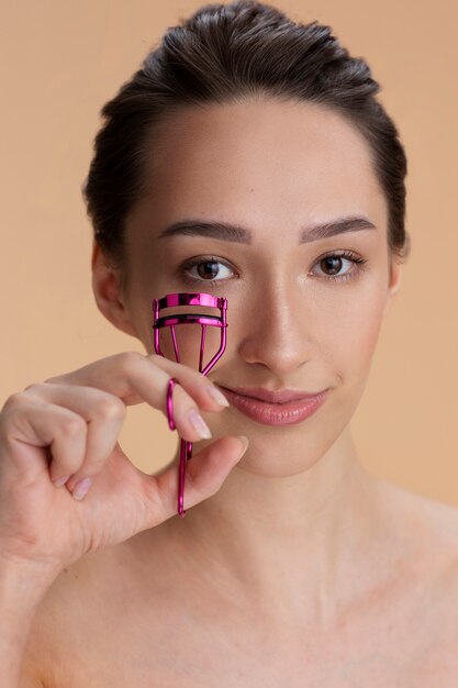 Vue de face femme utilisant un recourbe-cils