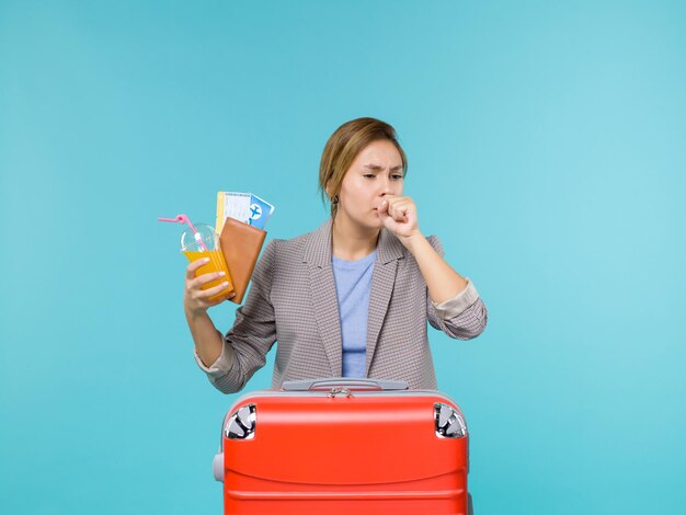 Vue de face femme en vacances tenant une boisson fraîche et des billets toussant sur fond bleu voyage de vacances voyage en mer voyage