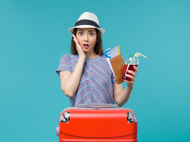 Vue de face femme en vacances tenant du jus avec des billets sur fond bleu femme mer voyage été voyage en avion