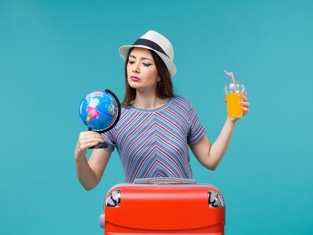 Vue de face femme en vacances tenant jus et globe sur le fond bleu mer voyage vacances été voyage voyage