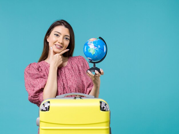 Vue de face femme en vacances tenant petit globe terrestre souriant sur fond bleu mer voyage été femme voyage vacances