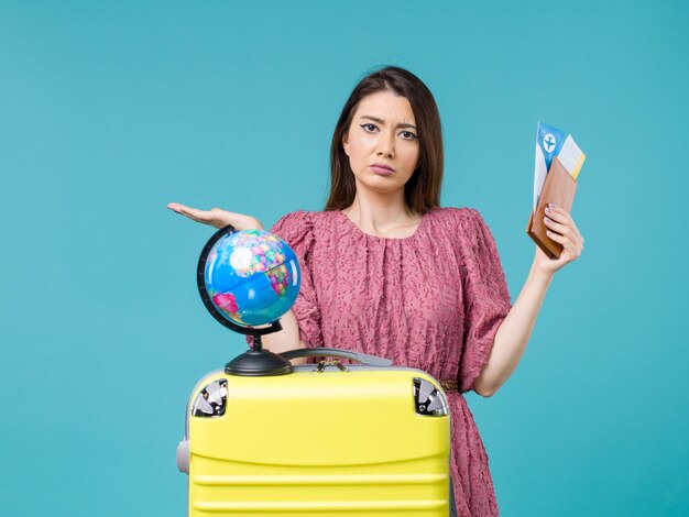 Vue de face femme en vacances tenant son portefeuille et billet sur un fond bleu clair mer voyage vacances femme voyage voyage