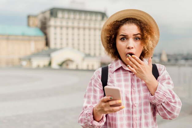 Vue de face femme vérifiant son téléphone lors d'un voyage