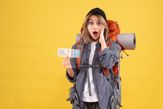 Vue de face d'une femme voyageur étonné avec sac à dos tenant un billet