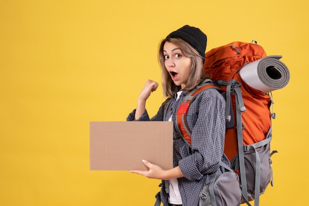 Vue de face de la femme voyageur excité avec sac à dos tenant le carton