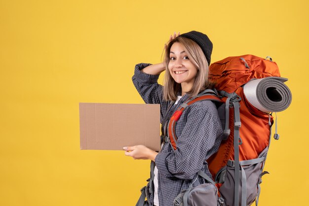 Vue de face de la femme de voyageur heureux avec sac à dos rouge tenant le carton