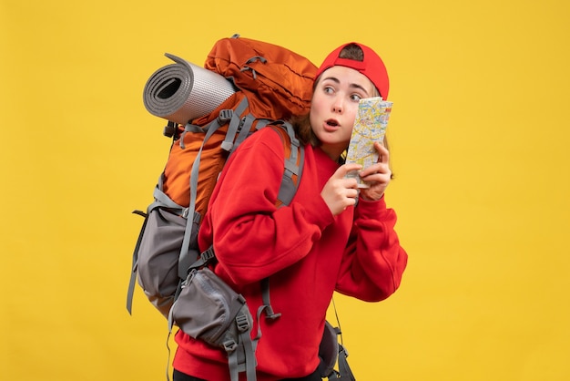 Vue de face femme voyageur intéressé avec sac à dos tenant la carte en regardant quelque chose