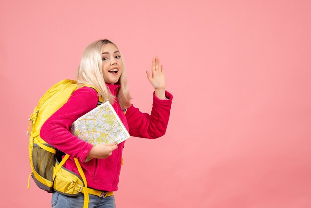 Vue de face femme voyageur avec sac à dos tenant la carte en agitant la main