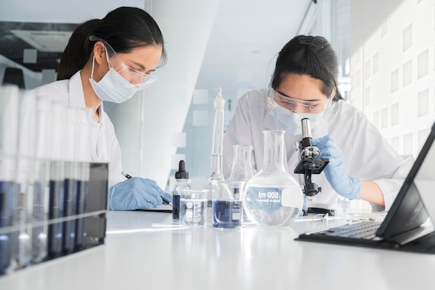 Vue de face des femmes asiatiques travaillant ensemble sur un projet chimique