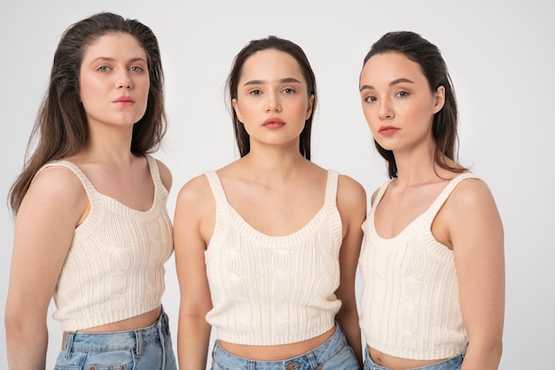 Vue de face de femmes en débardeurs et jeans posant dans des portraits minimalistes