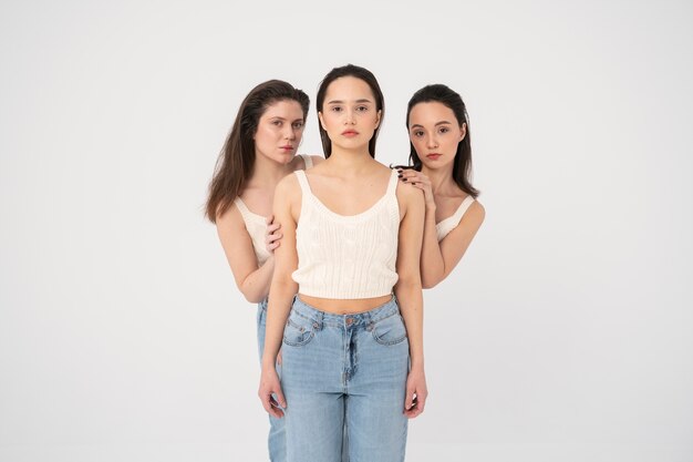 Vue de face de femmes en débardeurs et jeans posant dans des portraits minimalistes