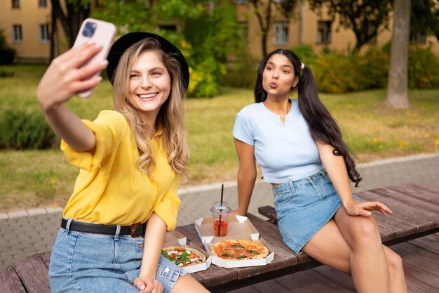 Vue de face femmes prenant selfie à l'extérieur