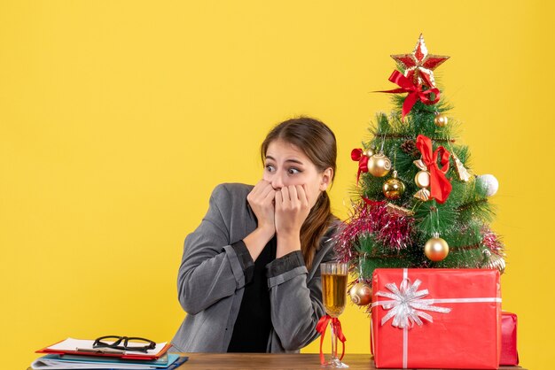 Vue de face fille aux yeux écarquillés assis à la table en mettant les mains