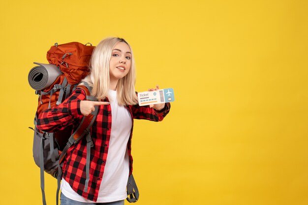 Vue de face fille blonde avec son sac à dos pointant sur son billet