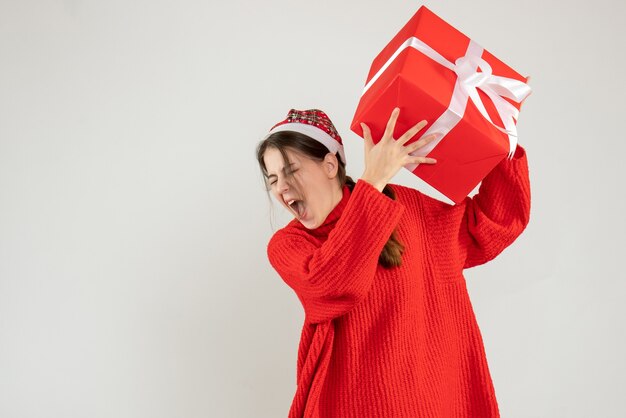 Vue de face fille en colère avec Bonnet de Noel tenant son cadeau de Noël