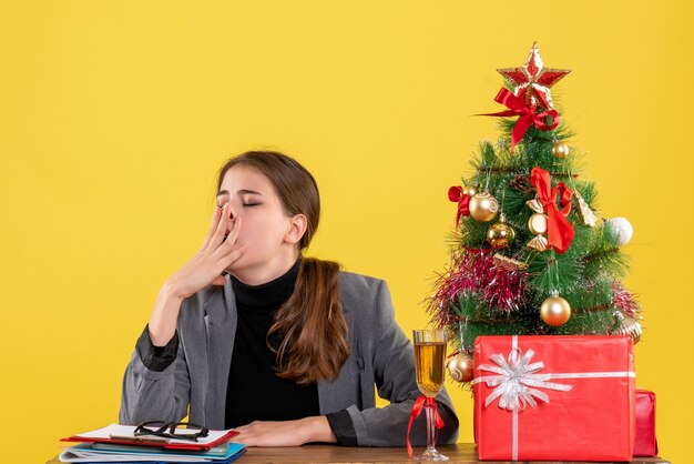 Vue de face fille endormie assis au bureau mettant la main