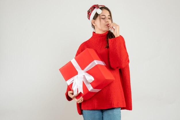 Vue de face fille heureuse avec bonnet de Noel tenant les yeux fermant le cadeau