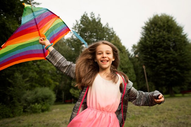 Vue de face d'une fille heureuse s'amuser avec un cerf-volant