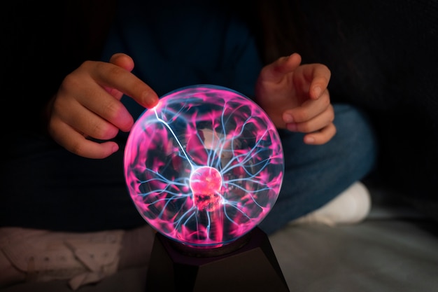 Photo gratuite vue de face fille interagissant avec une boule de plasma