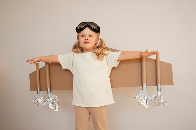 Vue de face fille jouant avec des ailes en carton