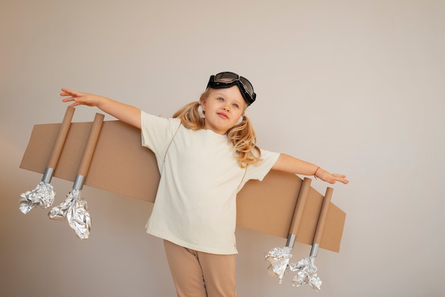 Vue de face fille jouant avec des ailes en carton