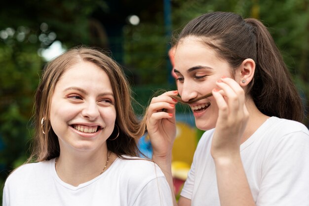 Vue de face fille jouant avec les cheveux de son amie