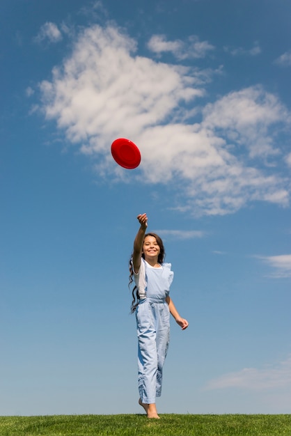 Photo gratuite vue de face fille jouant avec un frisbee rouge