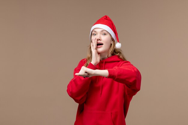 Vue de face fille de Noël chuchotant sur un fond marron vacances Noël émotion