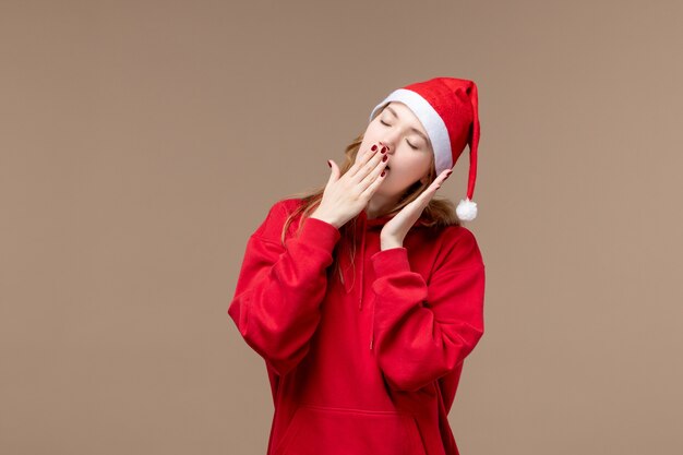 Vue de face fille de Noël essayant de dormir sur fond marron vacances Noël émotions