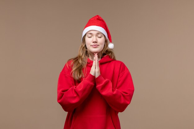 Vue de face fille de Noël avec expression de prière sur l'espace brun