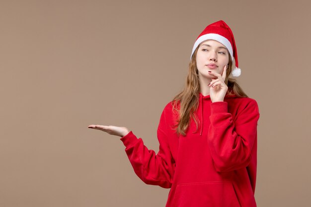 Vue de face fille de Noël pensant sur le fond marron vacances nouvel an Noël