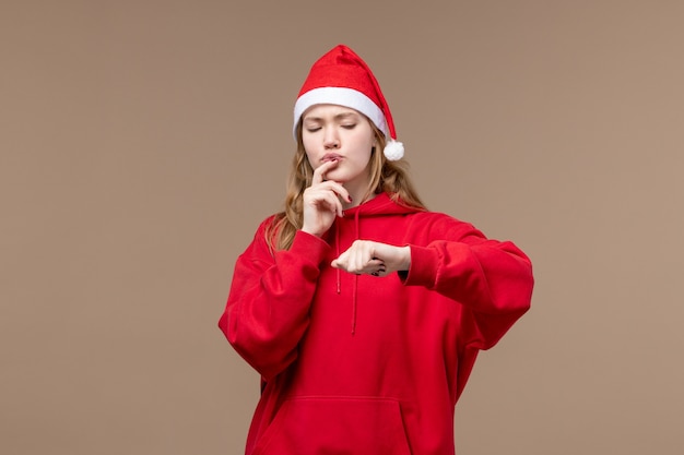 Vue de face fille de Noël vérifier le temps sur fond marron vacances Noël émotions