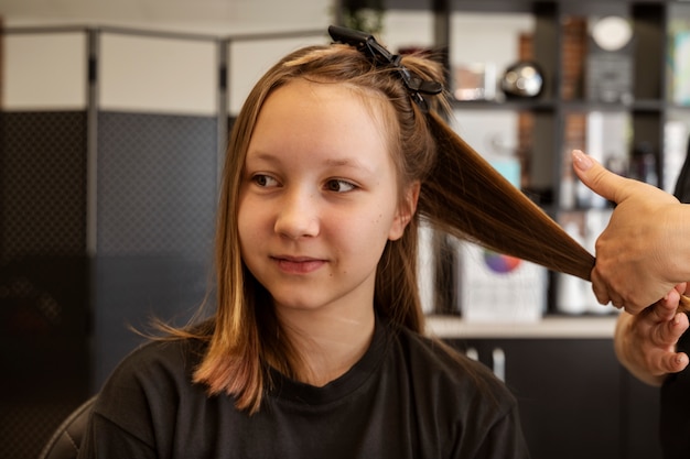 Photo gratuite vue de face fille se coupe les cheveux au salon