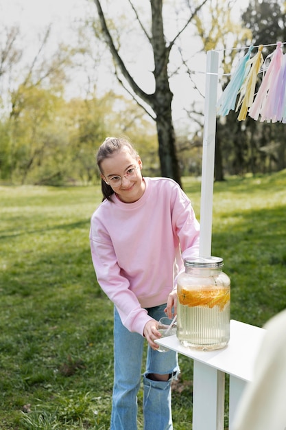 Vue de face fille souriante versant de la limonade fraîche