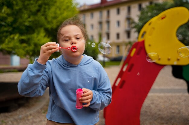 Vue de face fille avec le syndrome de down faisant des bulles de savon