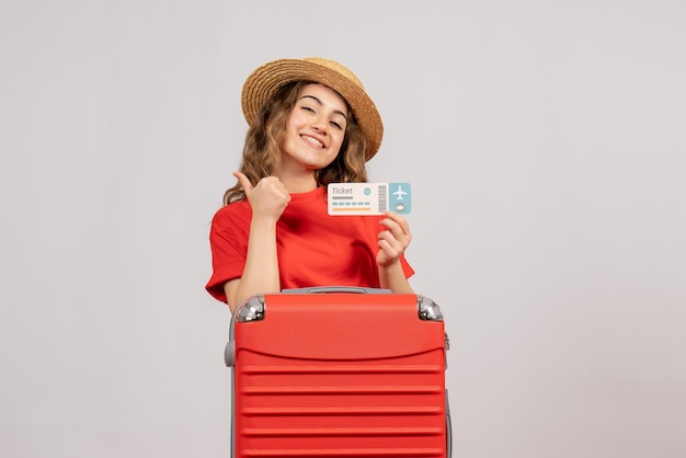 Vue de face de la fille de vacances avec sa valise tenant un billet donnant les pouces