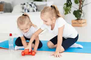 Photo gratuite vue de face des filles à la maison sur un tapis de yoga avec des poids